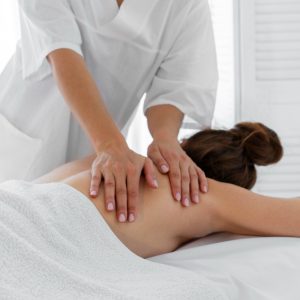 Pessoa deitada na cama, recebendo massagem nas costas