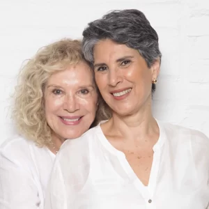 Janine Goossens e Natalie Florence estão abraçadas e vestidas de branco