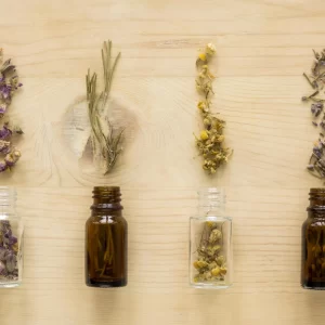 Foto de frascos de vidro lado a lado despejando ervas sobre uma mesa de madeira