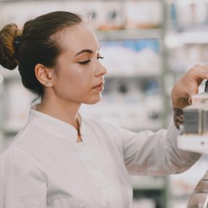 Mulher branca de cabelo preso escolhe produtos em uma prateleira