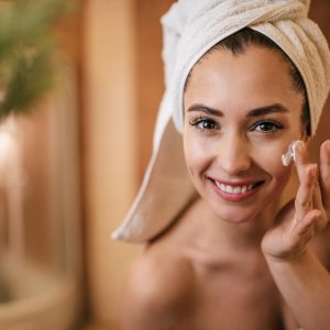 linda-mulher-aplicando-hidratante-no-rosto-no-banheiro